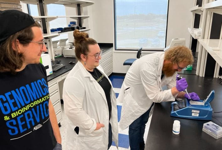 Scientists gather around a DS-11 Spectrophotometer at TxGen